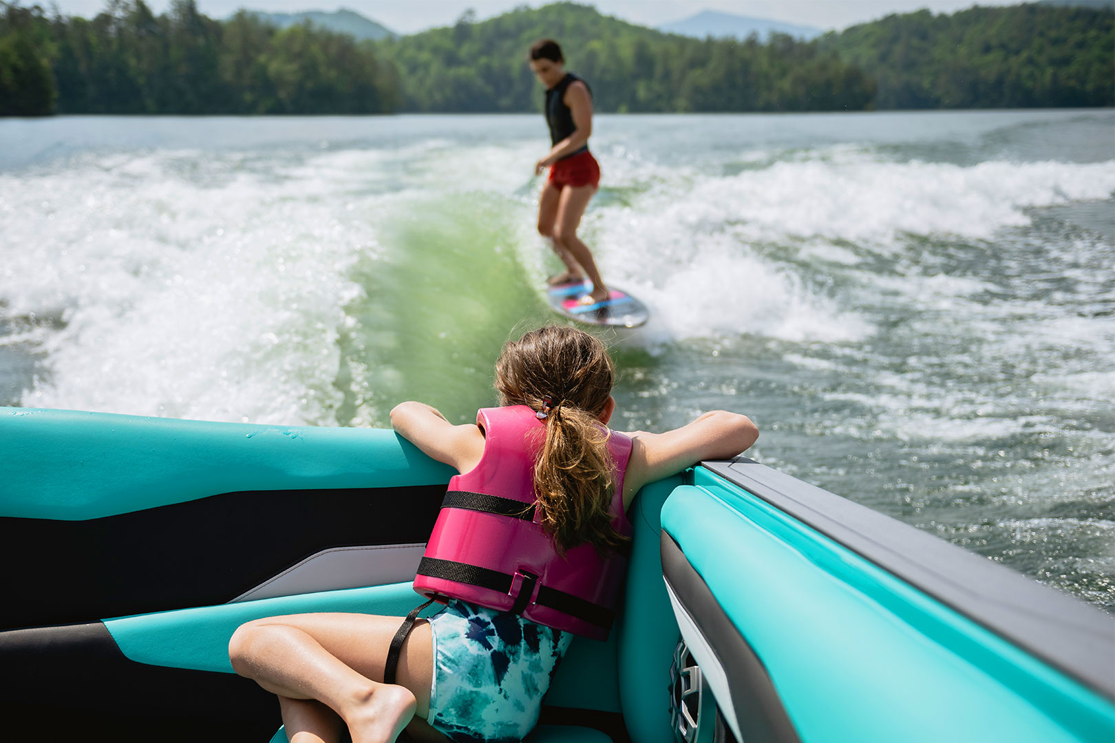Passenger Watching Wake Surfer from Rear of Boat