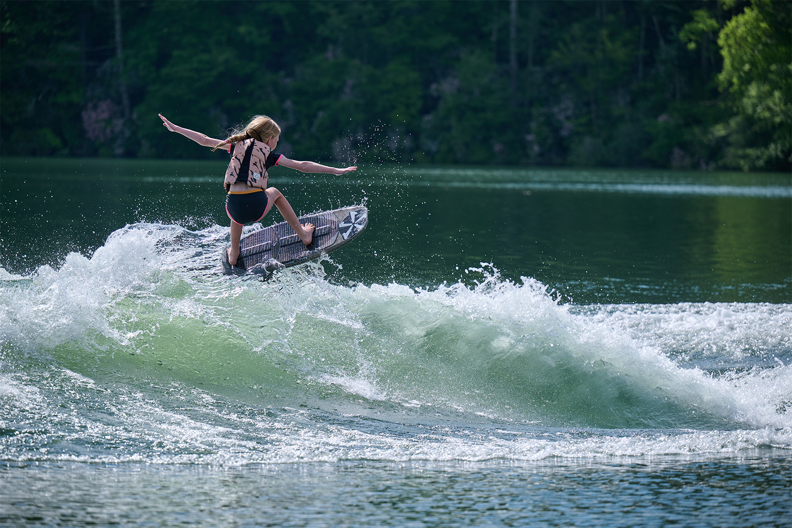 Close-up of Collins Neal catching air on a wakesurf wave behind the Axis T250, highlighting wave shape and performance.
