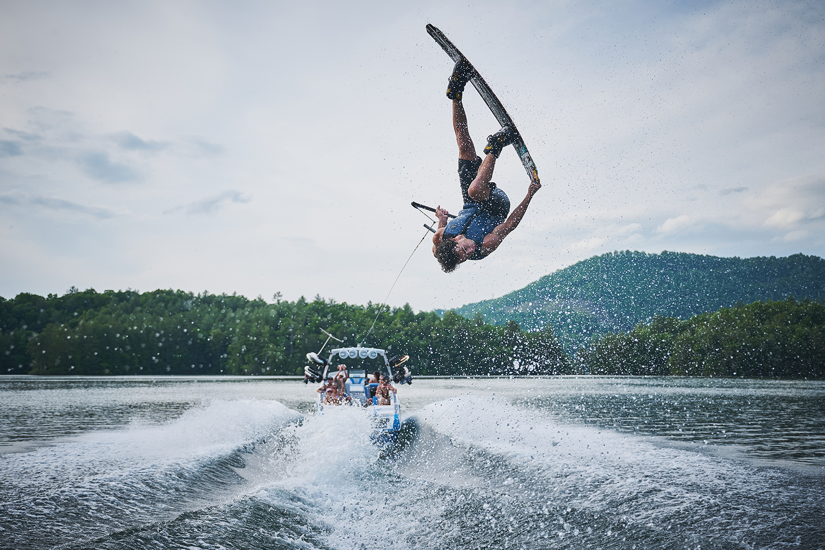 Rear view of Guenther Oka airborne while wakeboarding behind the Axis T250, wake visible beneath him.