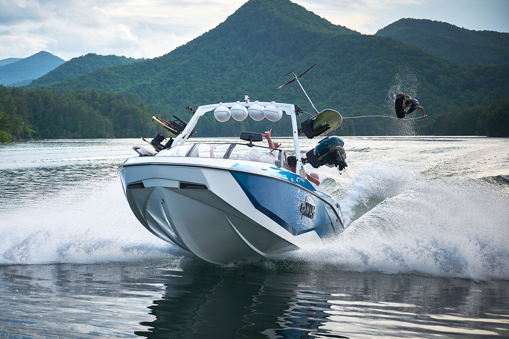 Bow view of the Axis T250 with a wakeboarder in the air behind the boat.