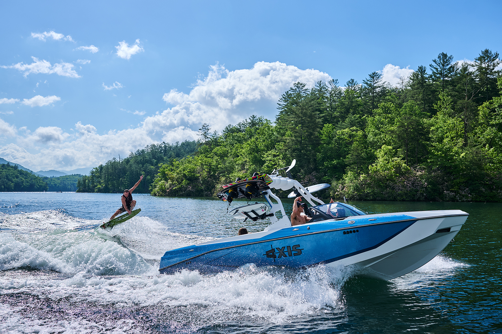 Full view of Johnny Stieg surfing behind the Axis T250 with the entire boat and wake visible.