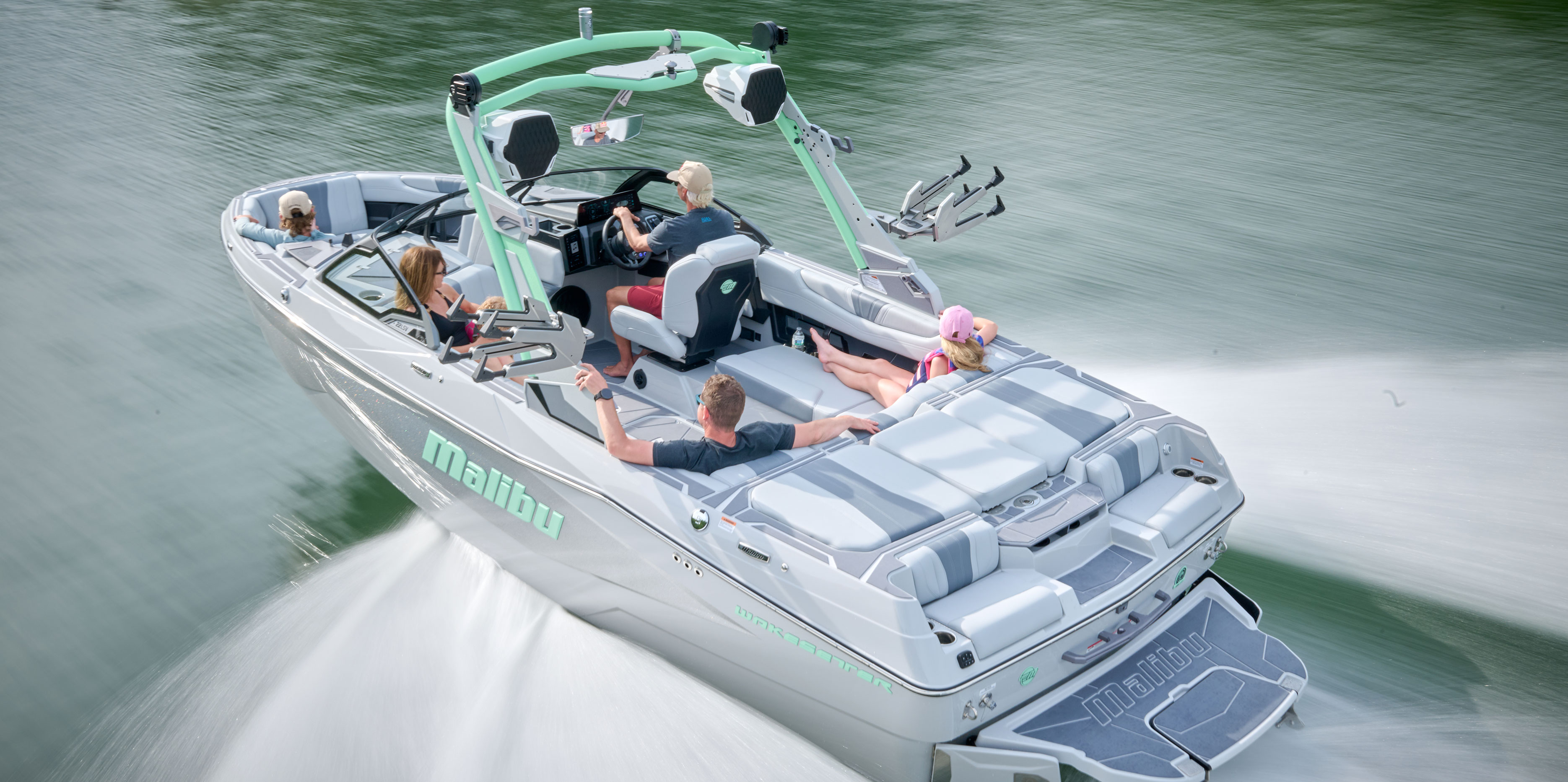 Malibu Wakesetter 22 LSV cruising across the lake with passengers enjoying the ride and the scenic backdrop.