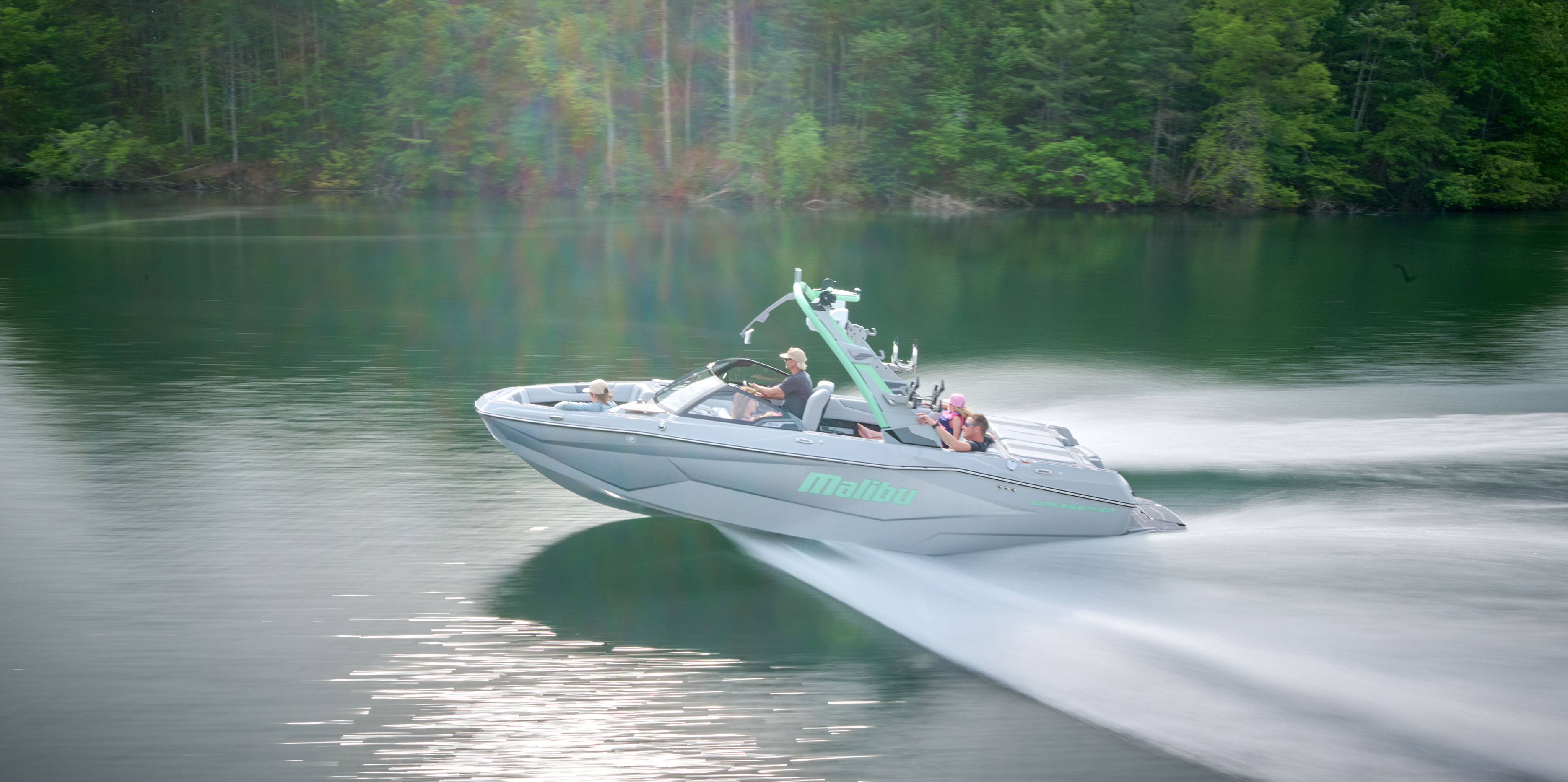 Side view of the Malibu Wakesetter 22 LSV towing a wakesurfer, with clean, powerful waves behind the boat.