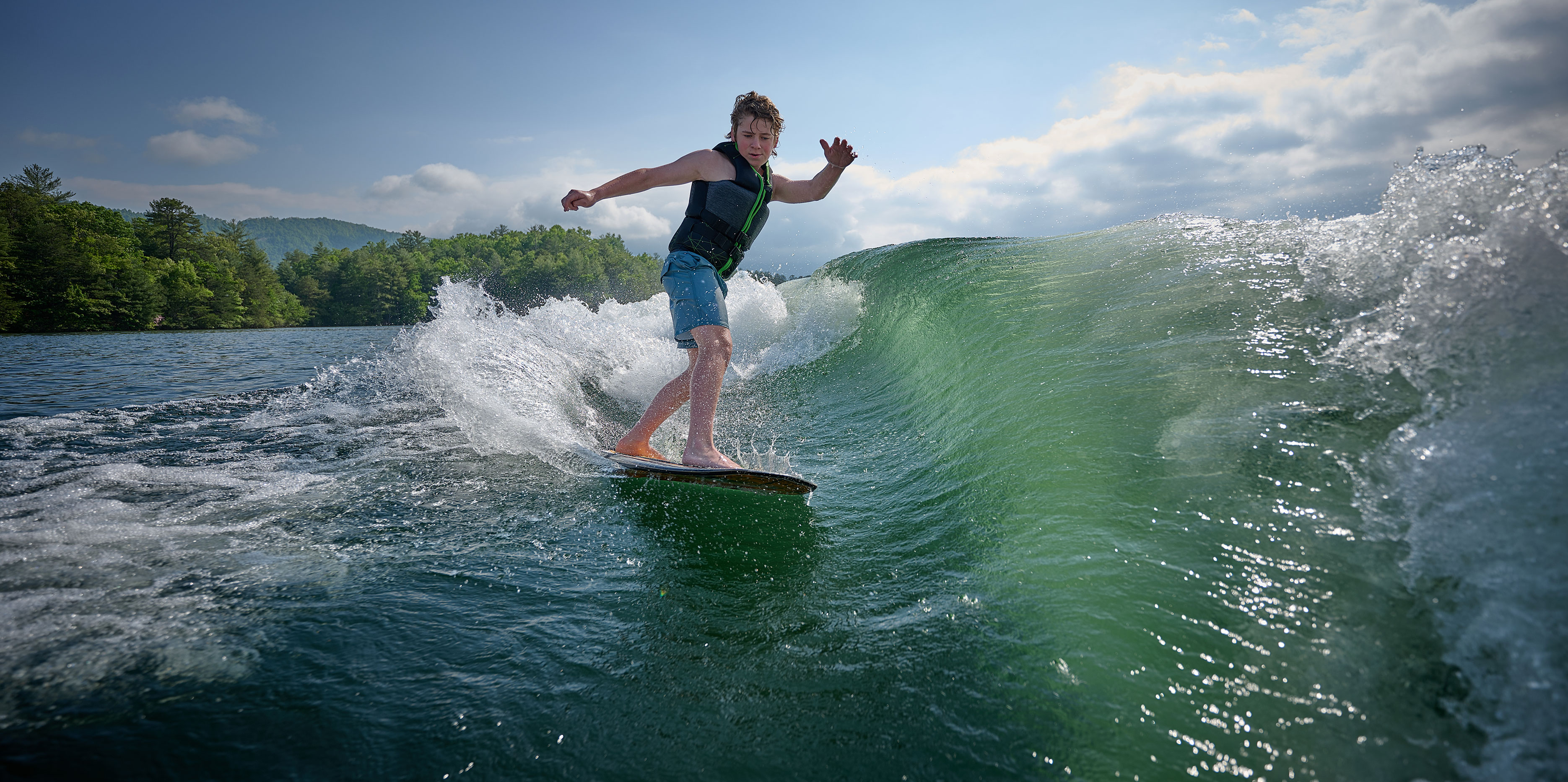 Wakesurfer carving behind the Malibu Wakesetter 22 LSV, showcasing wave height and clean shape.