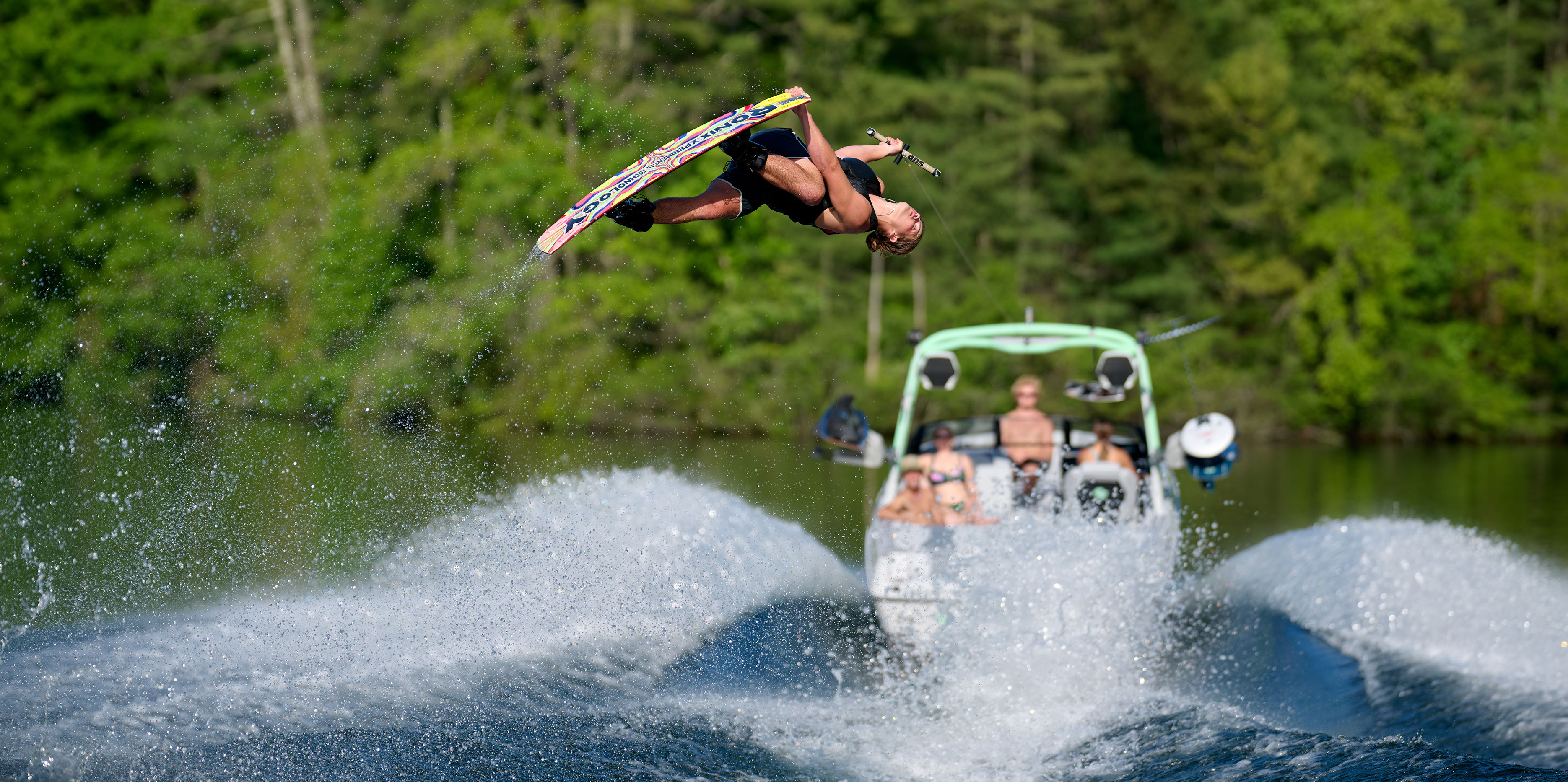 Wakesurfer riding closely behind the Malibu Wakesetter 22 LSV with clear water and a well-defined wave face.